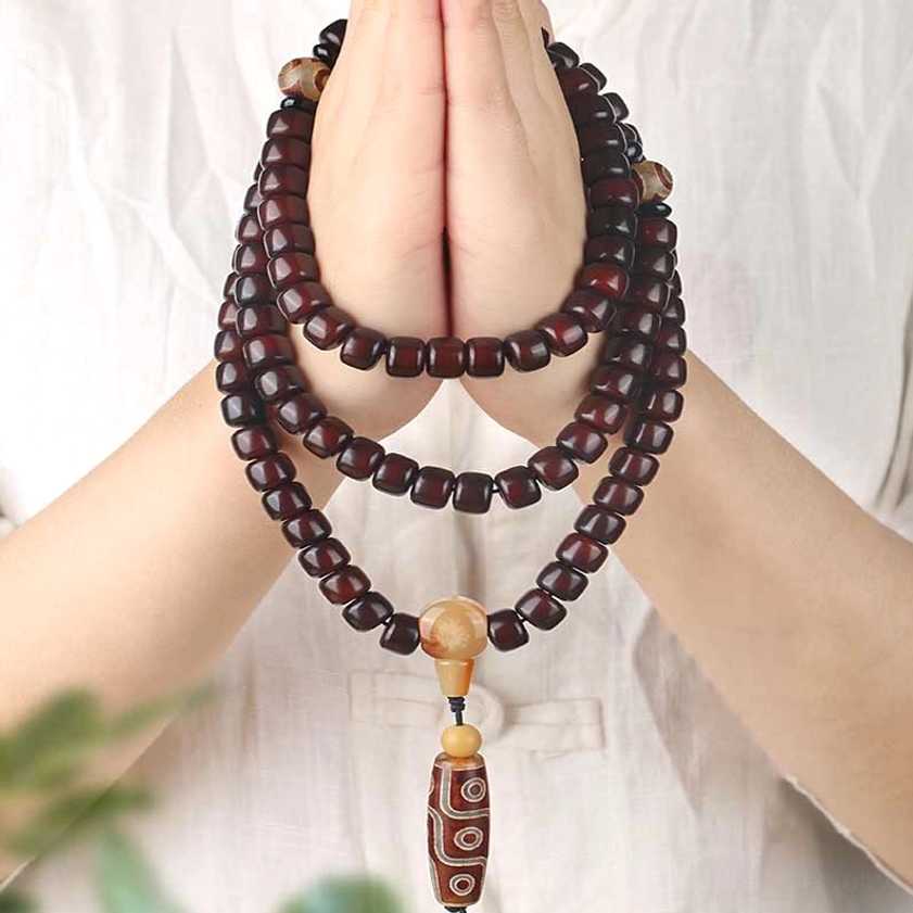 Buddhist dzi mala bracelet with three-eye and nine-eye stones worn on wrist, showing jade spacer beads and protective amulet design for daily wear and meditation