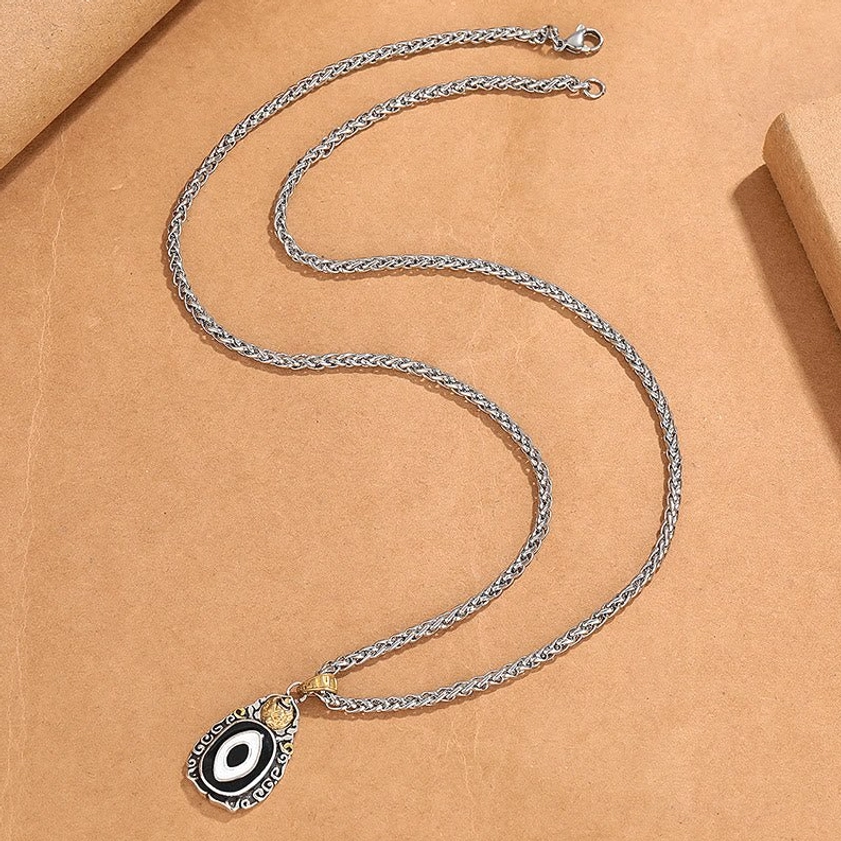 Side view of Garuda Dzi necklace with silver wheat chain and lobster clasp closure on brown paper background