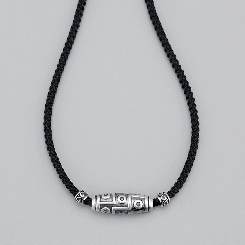 Buddhist dzi bead necklace material detail showing 999 sterling silver purity and black braided rope construction quality