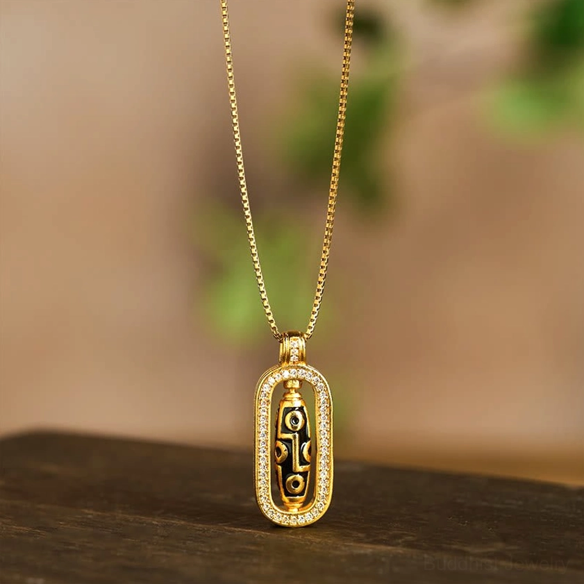 Nine-eye dzi necklace with classic rectangular CZ bordered pendant and simple chain on dark wooden surface