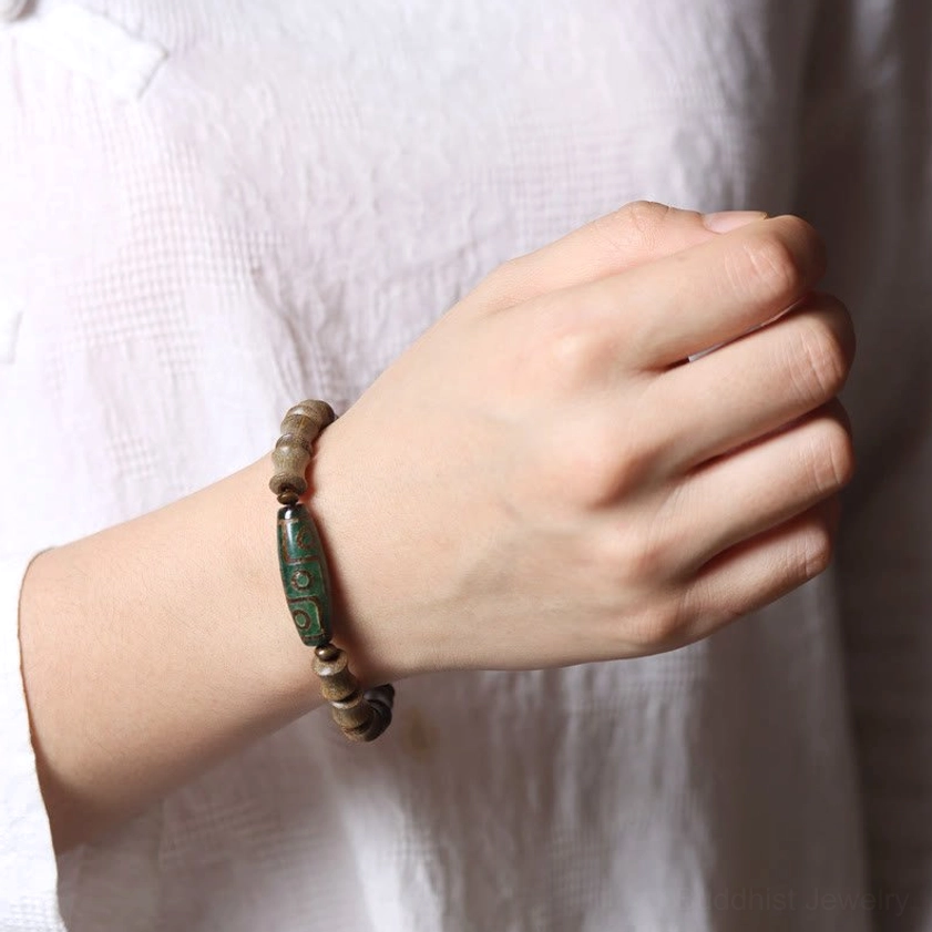 Nine-eye dzi green sandalwood Buddhist bracelet worn on wrist side view