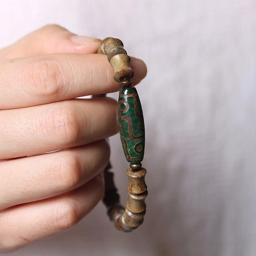 Nine-eye dzi green sandalwood Buddhist bracelet on right wrist showing comfortable fit