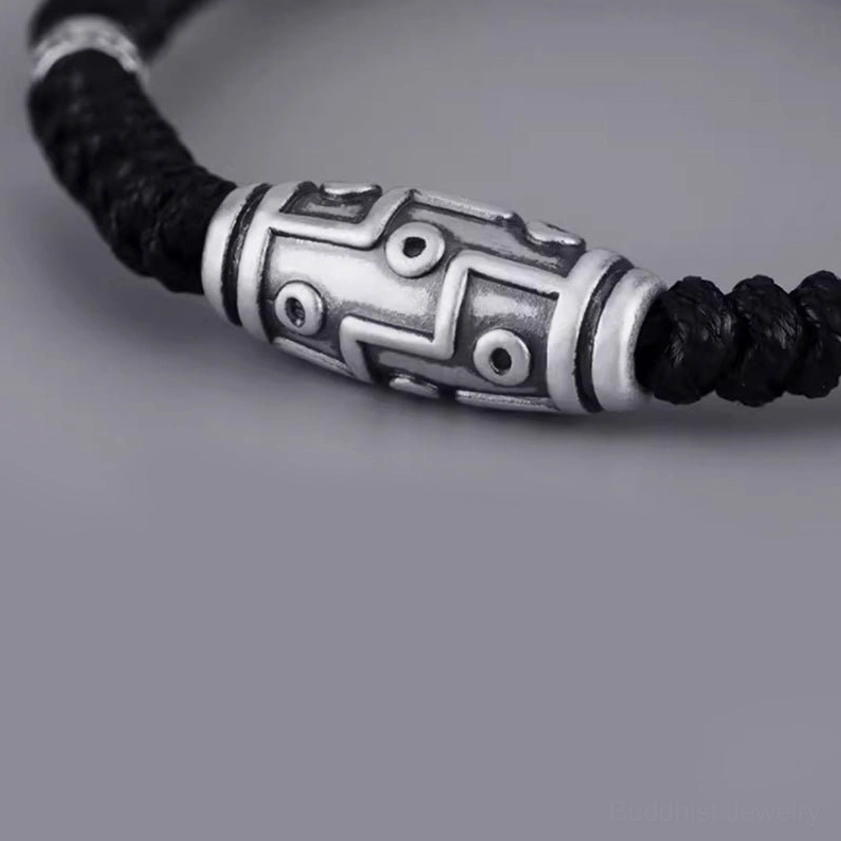 Close-up side view of nine-eye dzi sterling silver bead bracelet with full bead display and braided black rope cord