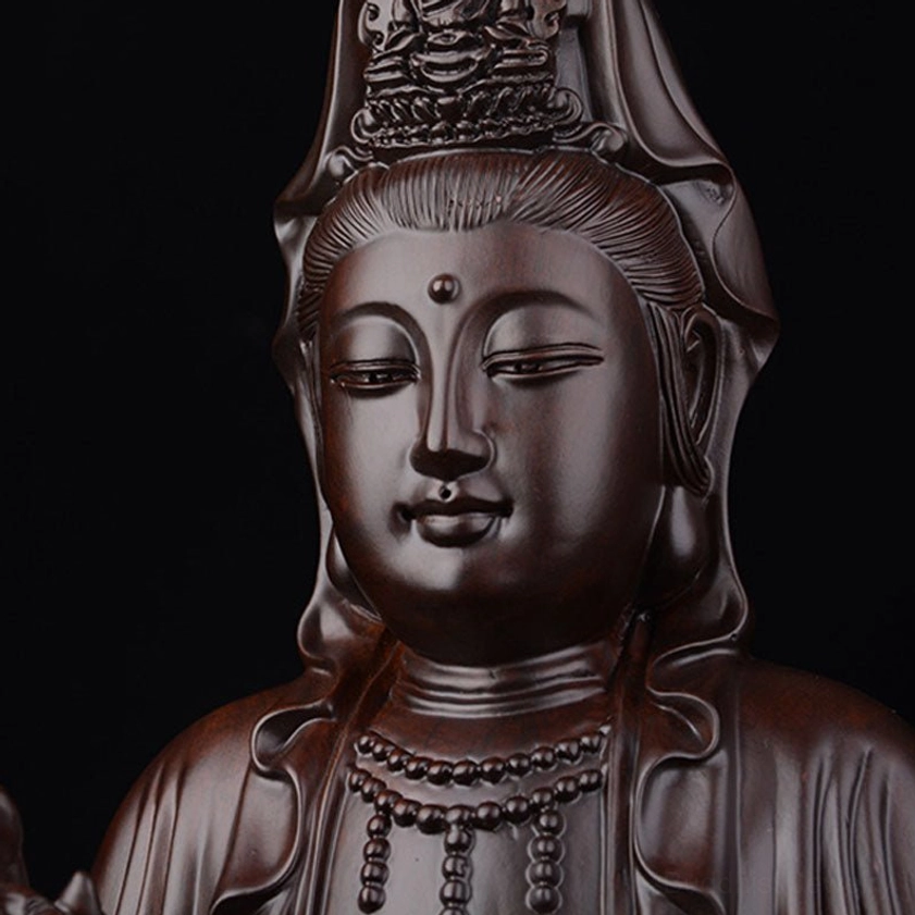 Close-up of ebony Avalokitesvara head with ornate crown and serene facial features, detailed carving