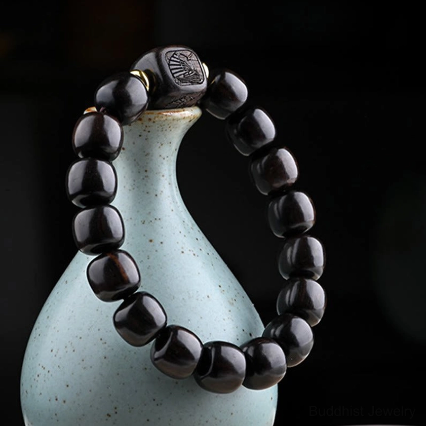 Close-up hanging shot of dark wooden barrel bead bracelet with carved decorative bead against porcelain vase background