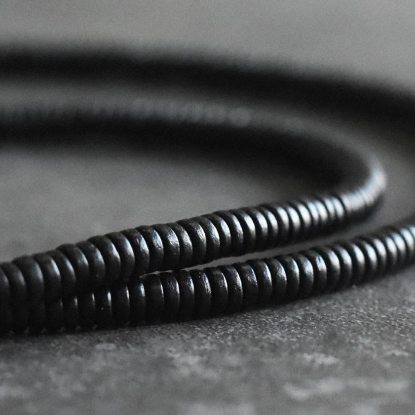 Precision close-up of tightly strung black ebony wood beads in Buddhist bracelet