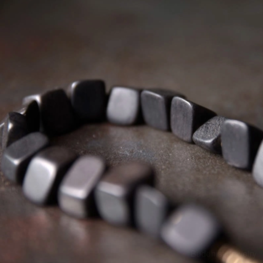 Individual black ebony wood bead with irregular square cut showcasing natural material grain and artisanal finish
