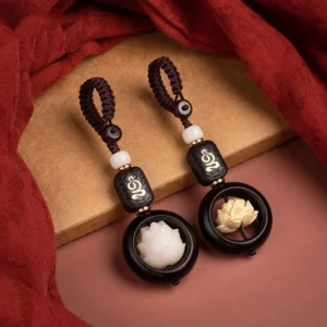 Ebony wood bodhi lotus keychain set with braided cord displayed on vintage red fabric and wooden surface