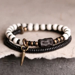 Ebony wood and bone bead couple bracelet set with copper accents, flat lay overhead view on dark fabric