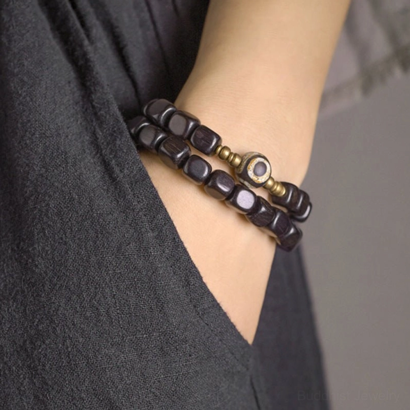 Multi-layered ebony wood bracelet with gold-toned copper spacers and eye dzi bead pendant charm