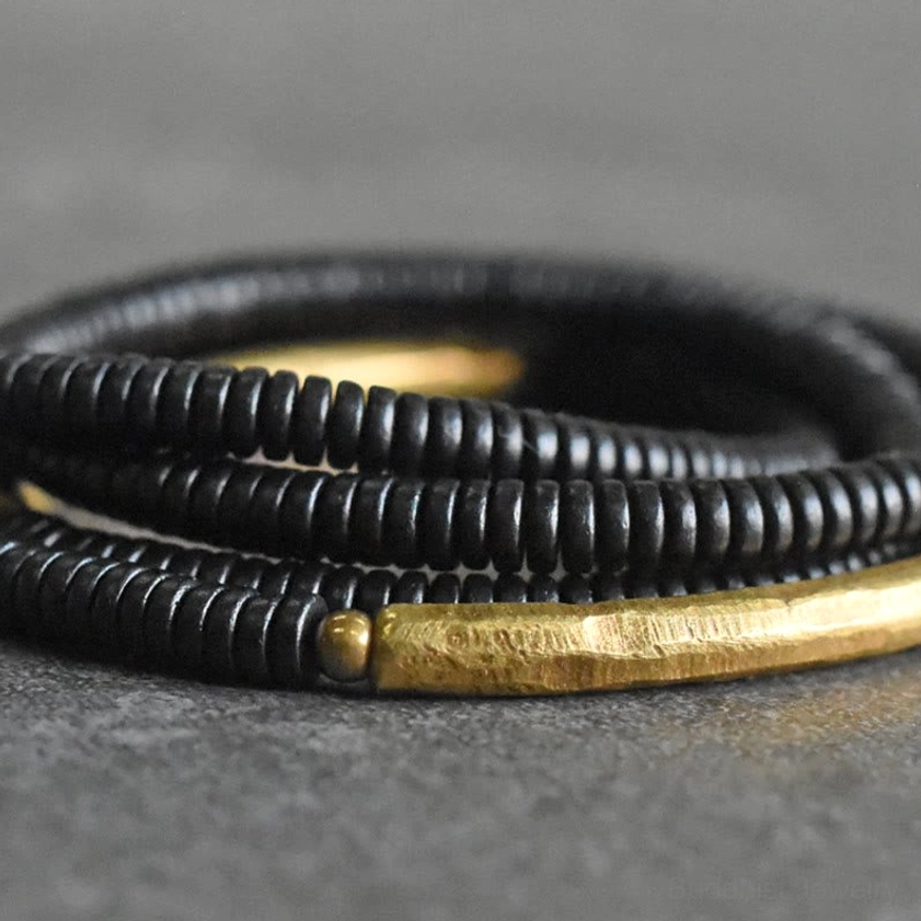 Close-up detail of ebony disc beads and hammered brass decorative strip on Buddhist bracelet