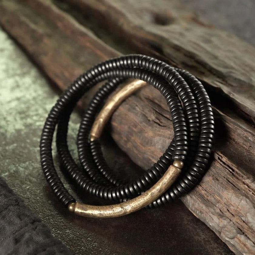 Handmade multilayered ebony bead bracelet with brass decorative elements on vintage wooden surface