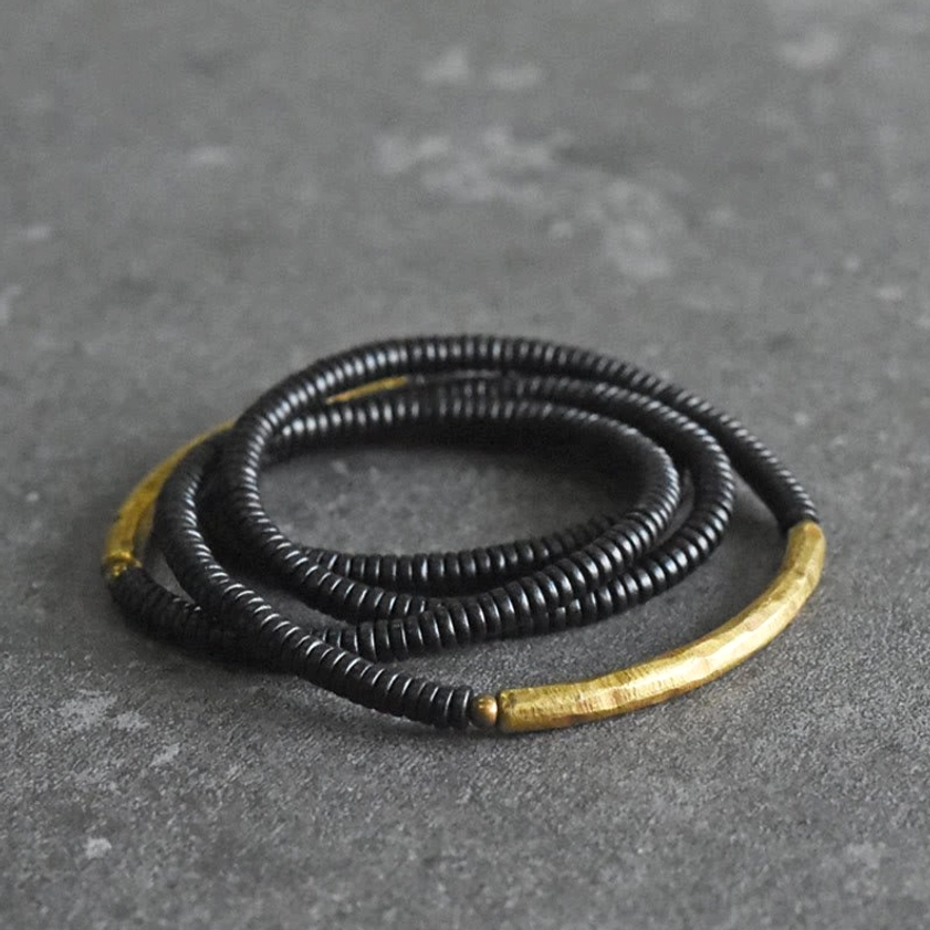 Multilayered ebony wood Buddhist bracelet with brass accents on gray surface
