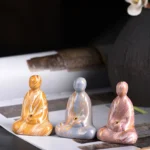 Handcrafted ebony wood Buddha incense holder with marbled lacquer finish, three-quarter front view on decorative mat