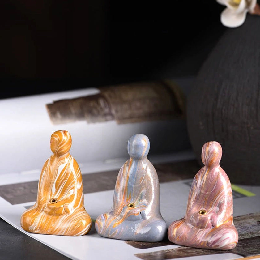 Handcrafted ebony wood Buddha incense holder with marbled lacquer finish, three-quarter front view on decorative mat