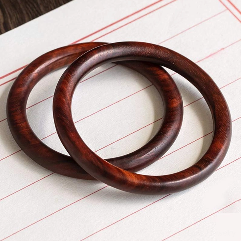 Two dark Ebony Wood Buddhist bangles interlocked on vintage paper - showing natural wood texture