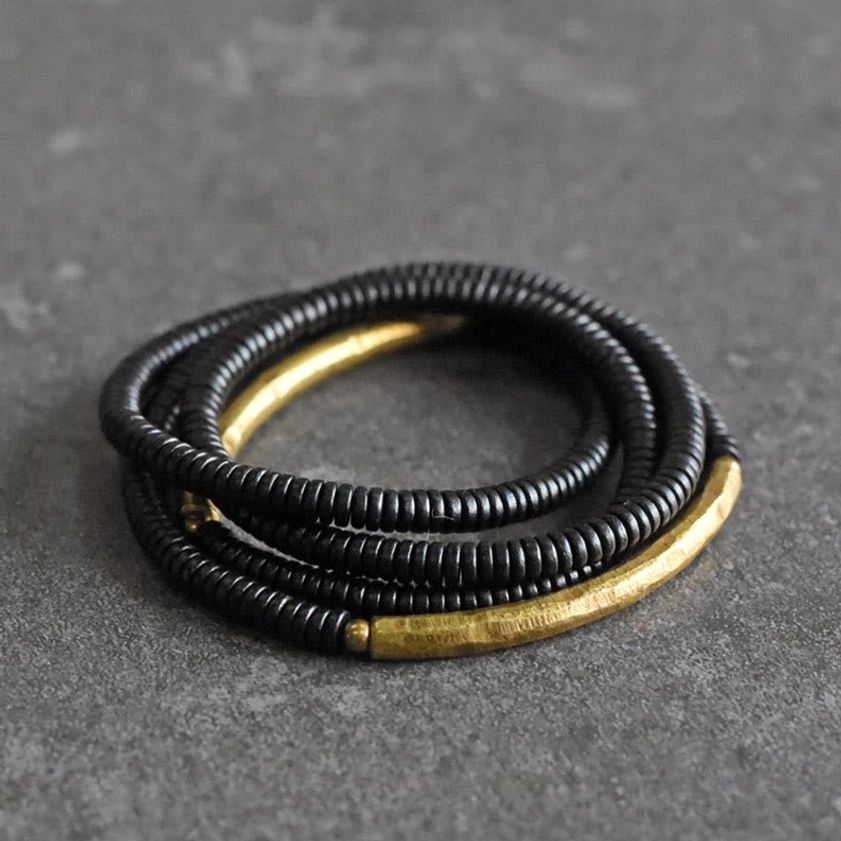 Flat overhead view of black ebony wood bead bracelet with brass hardware accent