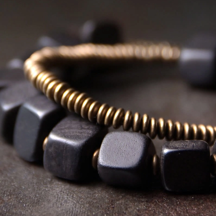 Close-up extreme detail of ebony wood beads and bronze copper metal components showing texture and craftsmanship