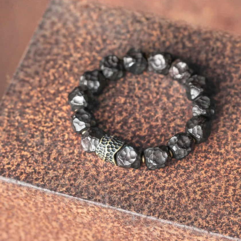 Vintage style ebony wood copper bracelet with carved silver-tone metal spacer on brown leather backdrop