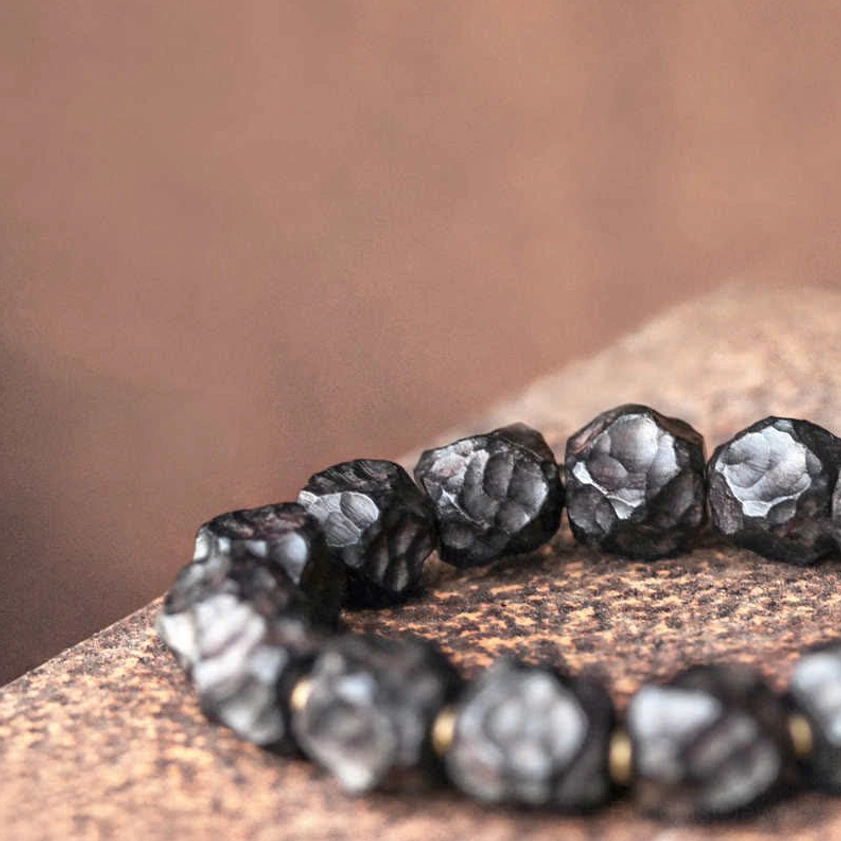 Close-up of hammered ebony wood beads showing detailed irregular texture and deep black matte finish