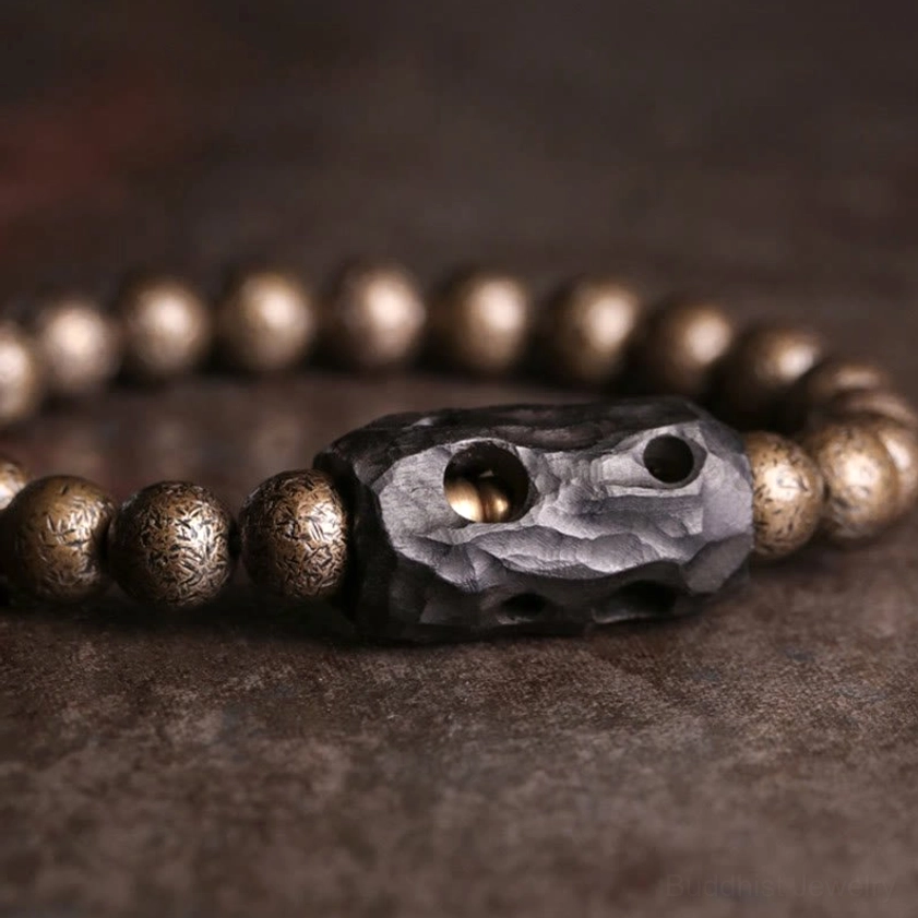 Close-up detail shot of ebony wood copper Buddhist bracelet featuring carved hollow ebony spacer bead and textured bronze accents