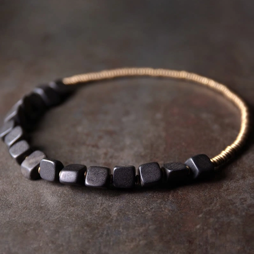 Black ebony wood beads and brass copper coils arranged in flat lay top-down composition on matte tabletop
