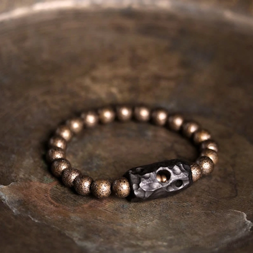Full view of ebony wood copper bracelet on dark stone-textured surface with all antiqued bronze beads fully visible