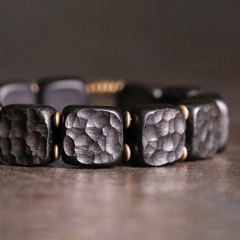 Hammered texture detail of ebony wood beads with bronze copper spacers in Buddhist bracelet design
