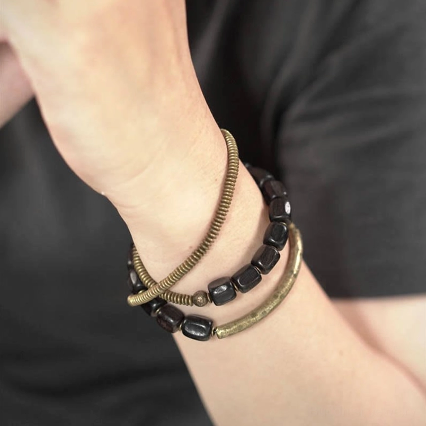 Worn Buddhist healing bracelet set with three stacked strands on wrist against dark clothing