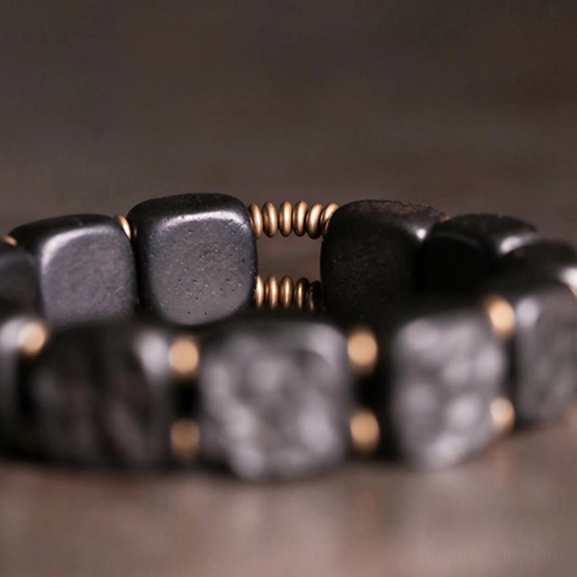 Extreme close-up of metal spring spacers between ebony wood square beads in copper-accented bracelet