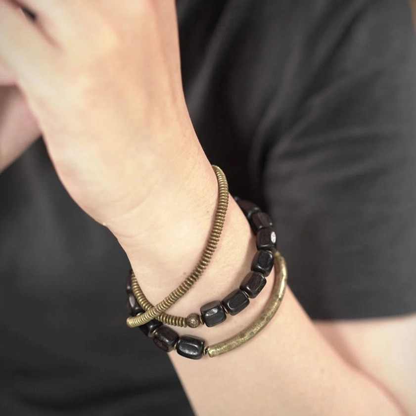 Three-strand Buddhist healing bracelet worn on wrist showing stacked ebony and copper layers