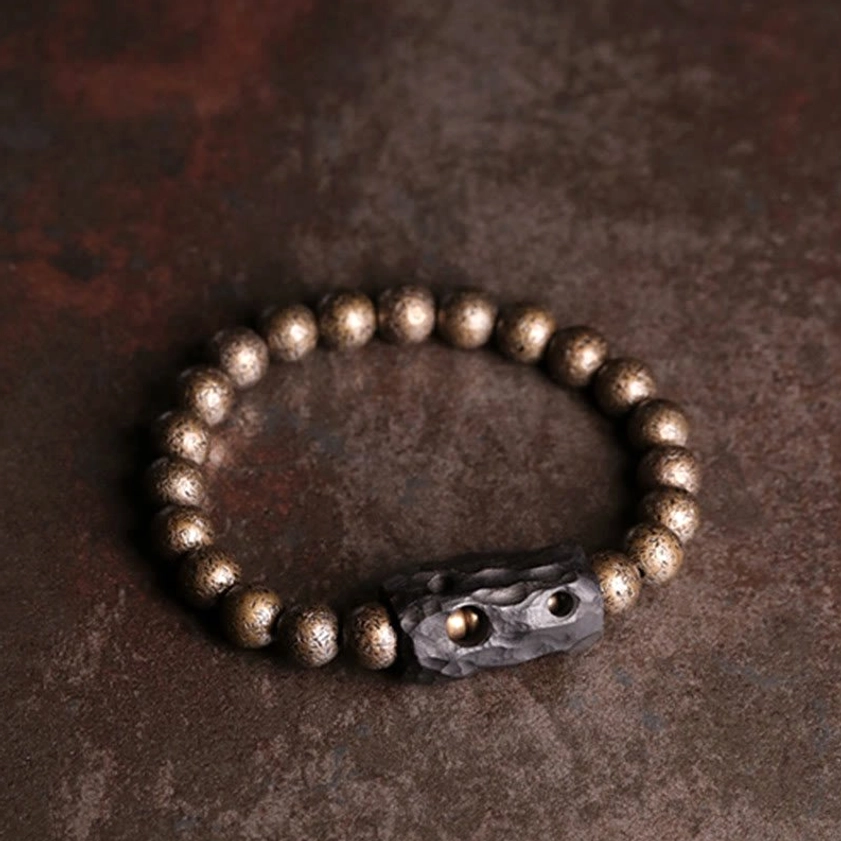 Ebony wood and copper Buddhist bracelet centered on dark reddish-brown wooden surface showcasing natural material authenticity