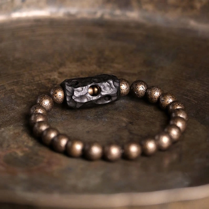 Ebony wood and copper beaded bracelet flat lay on dark rustic wood with alternate spacer orientation and full bead visibility