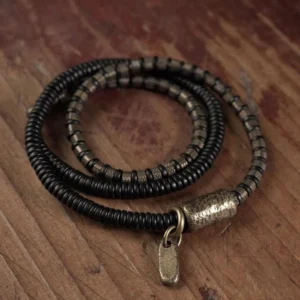 Ebony wood copper Buddhist healing bracelet top-down flat lay view with antique brass barrel beads and hanging metal tag charm