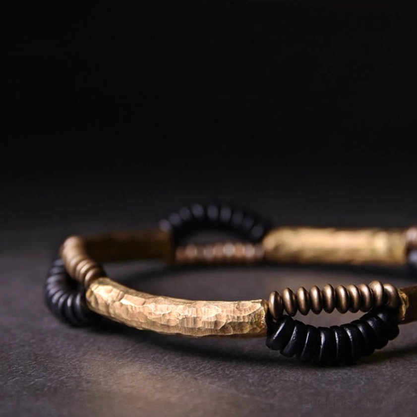 Close-up side profile of handcrafted ebony wood copper Buddhist bracelet with textured copper bars and twisted black wooden beads on black background