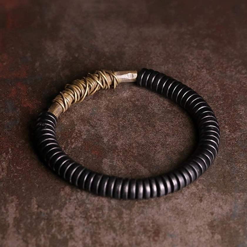 Side profile of ebony wood and copper Buddhist bracelet displaying two-tone minimalist design with black beads and brass metalwork accent