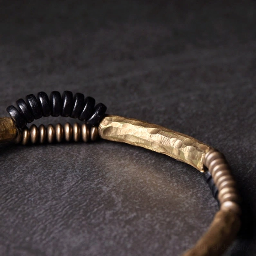 Single handmade ebony wood and copper Buddhist bracelet close-up side flat lay showing hammered copper tube and mixed black bronze spacer beads