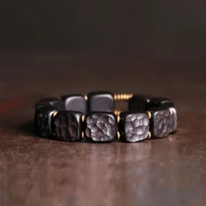 Ebony wood and copper square bead Buddhist bracelet with textured beads and antique bronze metal spacers, overhead flat lay view