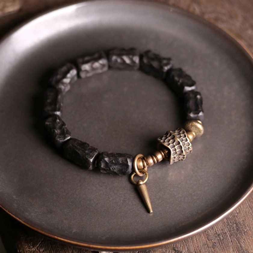 Dark ebony wood copper bracelet on metallic plate featuring hammered bronze bead and spike pendant design