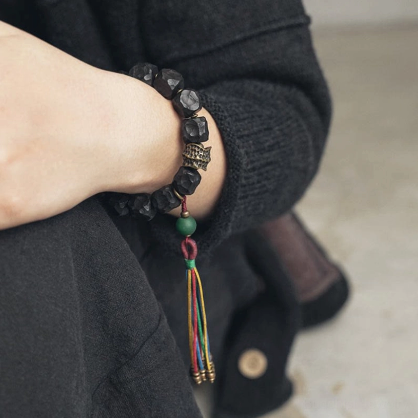Buddhist mala bracelet on wrist paired with casual dark outerwear - wearable mindfulness