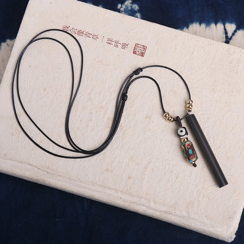 Pair of handcrafted ebony wood dzi bead necklaces with adjustable wax cords on calligraphy notebook