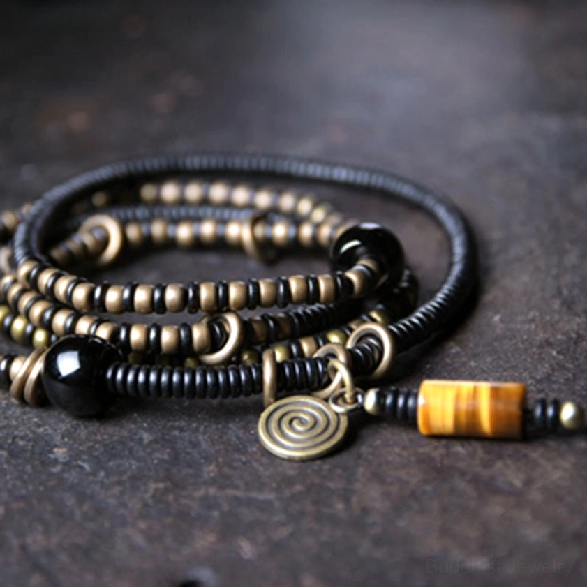 Ebony wood dzi bead copper peace bracelet set overhead flat lay on dark stone showing protective amulet design with spiral charm