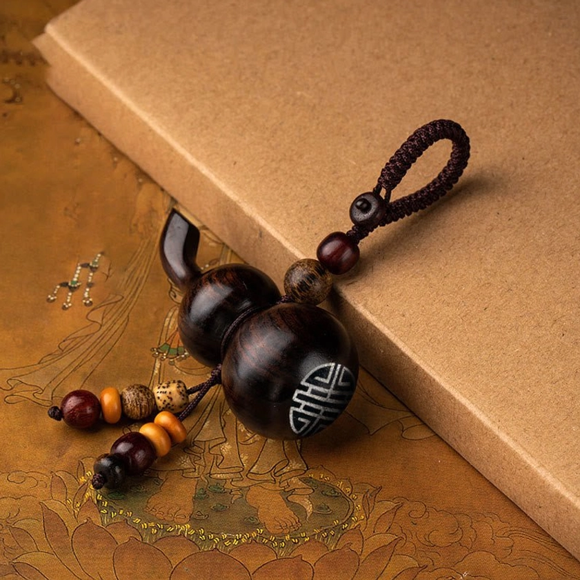 Ebony gourd keychain with double happiness engraving and beaded tassel, featuring natural dark brown wood grain for spiritual protection