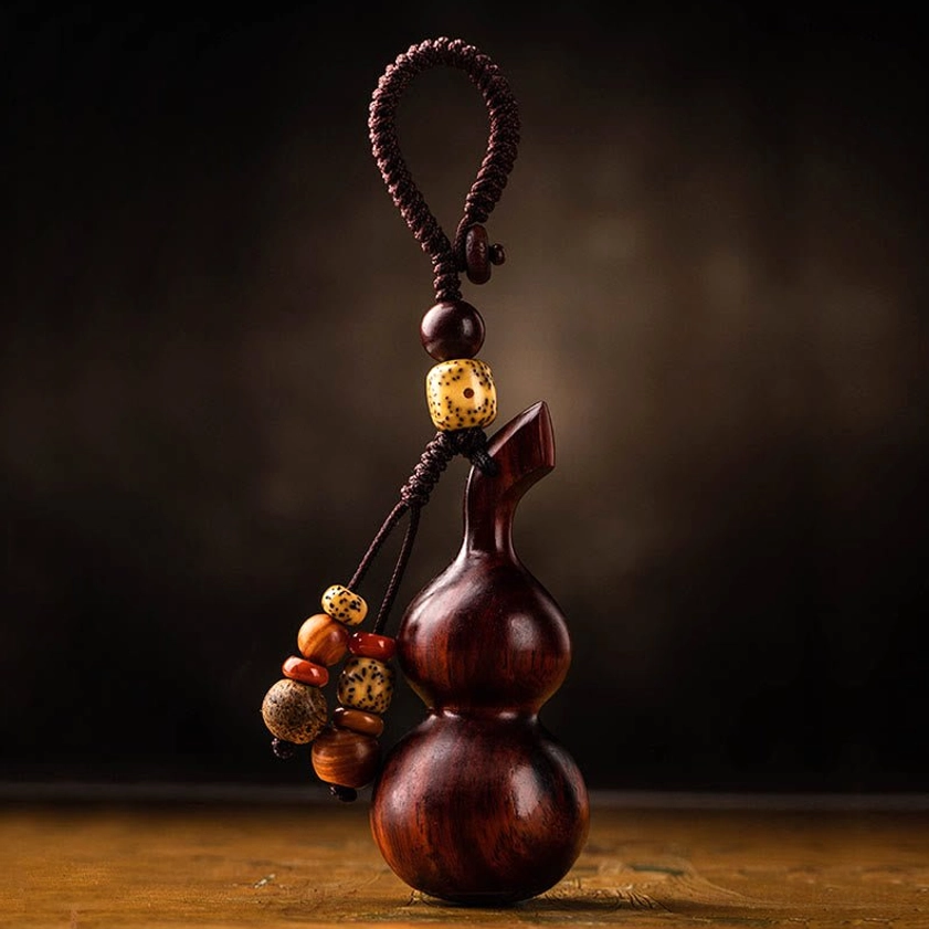 Handmade ebony gourd keychain displaying traditional Buddhist symbolism with protective engraving and natural wood finish