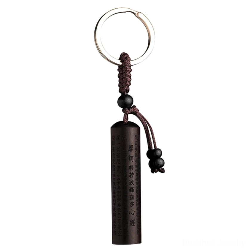 Single ebony wood Heart Sutra keychain with brown braided cord and black bead accents in flat lay view