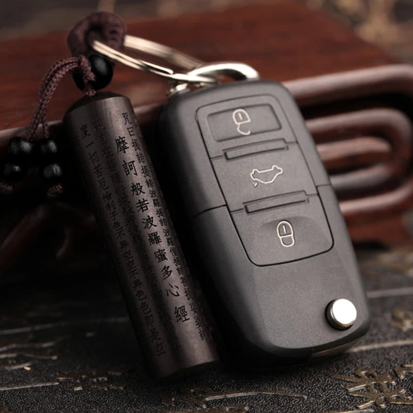 Heart Sutra ebony keychain paired with modern car key, demonstrating practical daily use and scale on wooden surface