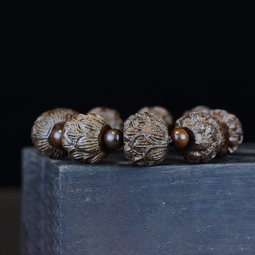 Ebony lotus carved bracelet front close-up view on dark wooden block, displaying neat arrangement of embossed lotus beads