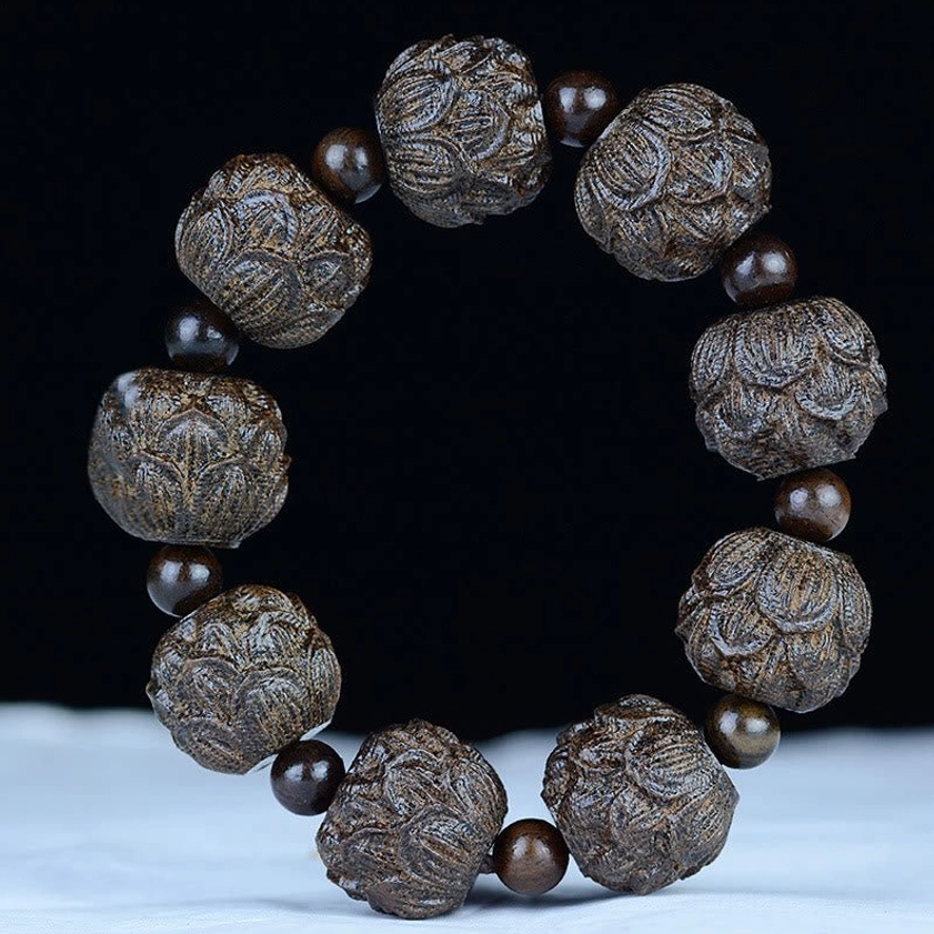 Lotus carved ebony wood Buddhist bracelet from above, displaying intricate lotus flower engravings on each bead with brown spacer beads