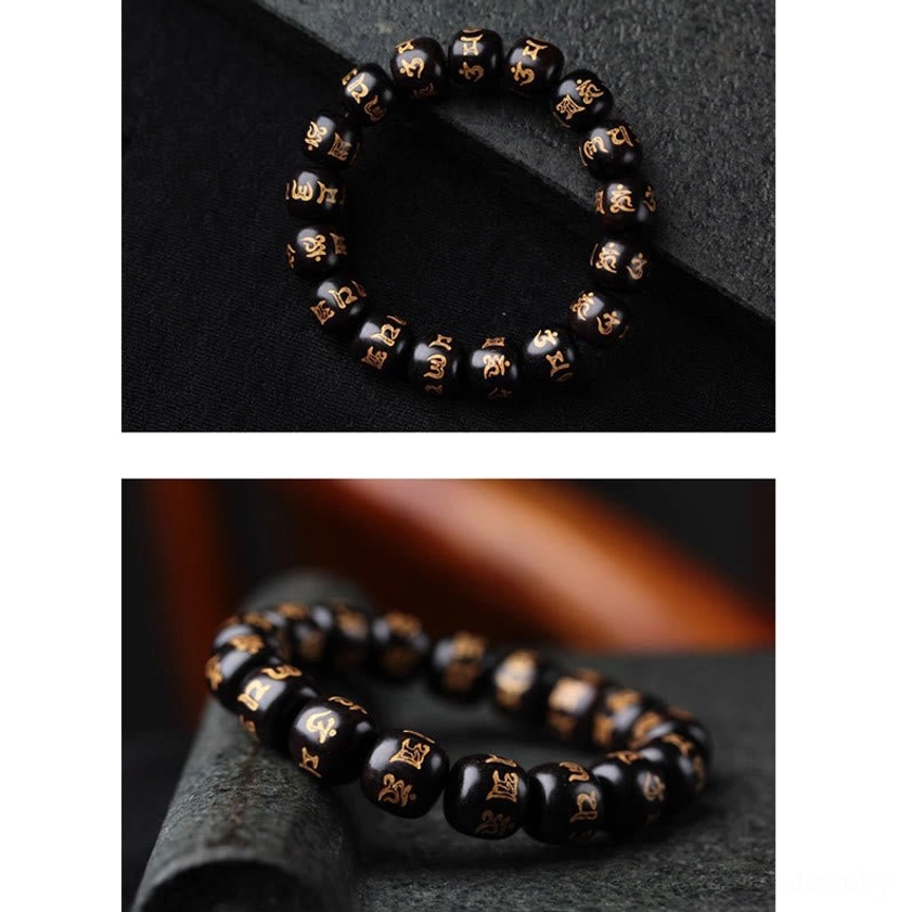 Compact ebony prayer bead bracelet with barrel-shaped beads and mantra engravings, top-down desktop view