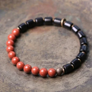 Ebony wood and red jasper Buddhist bracelet flat lay on rustic wooden surface showing natural gemstone beads and copper spacers